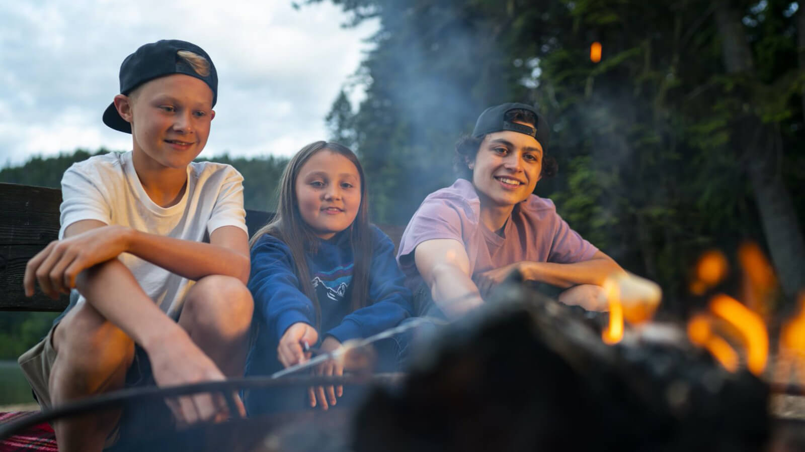 Kids smiling beside a campfire